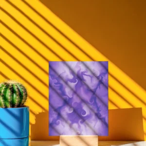 A mini unframed abstract fine art print, propped on a small wooden stand against a yellow wall. Sunlight casts a striped shadow across the artwork and the wall.