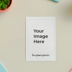 A polaroid photo mockup centered on a beige desk, surrounded by colorful notepads, a succulent in an orange pot, and a coffee cup, conveying a creative workspace.