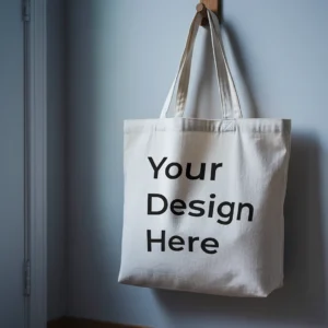 A tote bag mockup hangs on a wooden hook against a light gray wall, creating a minimalist and serene atmosphere.